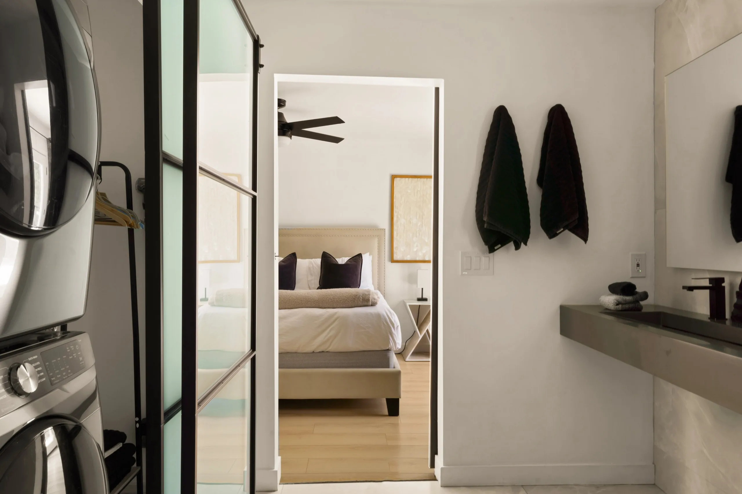 Through an open steel-framed door to a made bed and a stone vanity, The Villa Palms, Indio, California